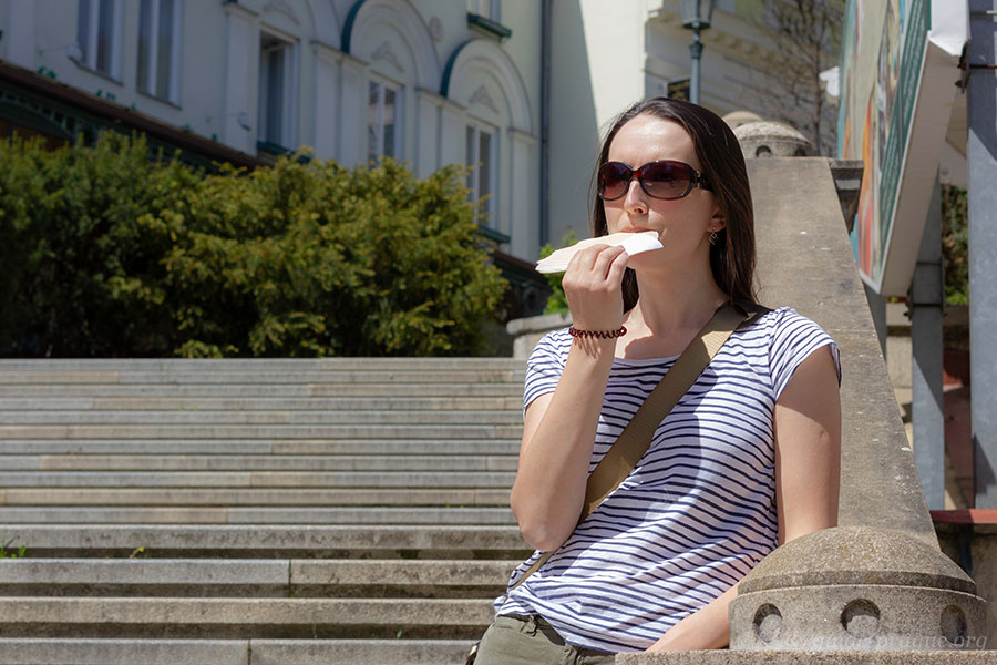 Photo of a woman eating a warm oplatka in Karlovy Vary.